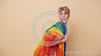 Youth asian transgender LGBT with Rainbow flag on shoulder isolated over nude color background. Man with a gay pride flag concept Stock Photo