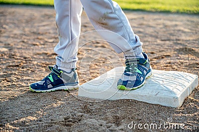 Youth baseball with a runner safe on base with a left foot tagged Stock Photo