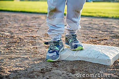 Youth baseball with a runner safe on base with a left foot tagged Stock Photo