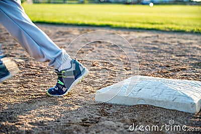 Youth baseball with a runner taking off for the next base Stock Photo