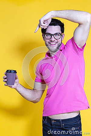 Youth lifestyle. Smiling Handsome Young Man With Sincere Beautiful Toothy Smile Posing With Coffee Cup on Yellow Background While Stock Photo