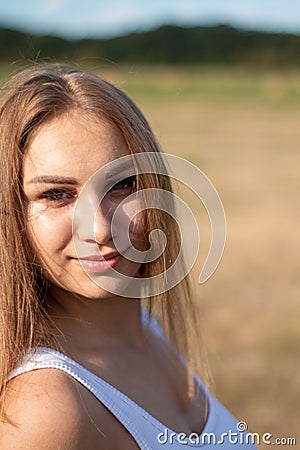 Youthful female stands in a picturesque outdoor setting, her expression thoughtful Stock Photo