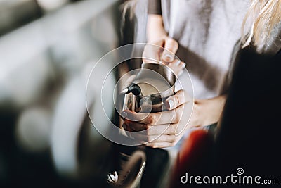 A youthful slim pretty blonde girl,dressed in casual outfit, is holding a milk frother in a cozy coffee shop. Stock Photo