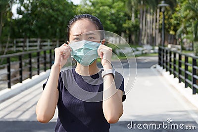 The ypung woman in medical protective mask relaxing in the park. campaign to use protective mask from COVID19 Stock Photo