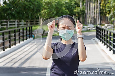 The ypung woman in medical protective mask relaxing in the park. campaign to use protective mask from COVID19 Stock Photo