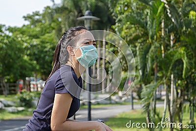 The ypung woman in medical protective mask relaxing in the park. campaign to use protective mask from COVID19 Stock Photo