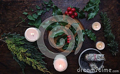 Yule winter solstice Christmas themed flat lay with branch of holly plant on a dark wooden table Stock Photo