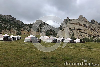 Yurt camp surrounded by trees on the ridge of the mountain. Small ger huts on the crest of the hill on a cloudy day Stock Photo
