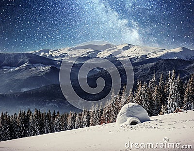 Yurt in the snow in the winter forest. Starry sky over the mountain peaks Stock Photo