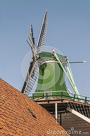 Old green dutch windmill standing between houses Stock Photo