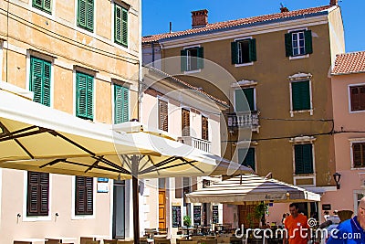 Zadar, Croatia; 07/17/2019: Facade of traditional croatian houses and parasols of the terraces of bars in the old town of Zadar Editorial Stock Photo