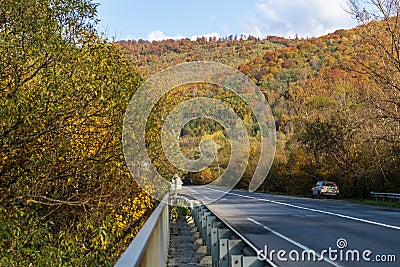 Among the mountains, on the side of a deserted asphalt road, there is a parked car. Editorial Stock Photo