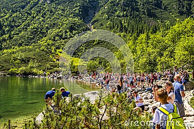 Zakopane, Poland - Crowds of tourists enjoying sunny weather and mountains scenery at the Morskie Oko pond in High Tatra Mountains Editorial Stock Photo