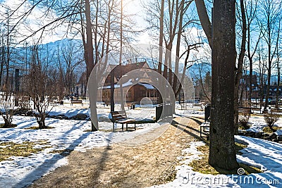 Zakopane, Poland - February 21, 2019. Park in the city covered with snow with a beautiful wooden house. Visible trees, sidewalk wi Editorial Stock Photo