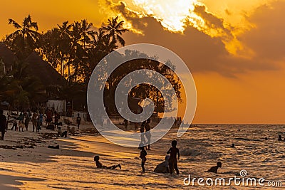 Zanzibar, Tanzania - 05 January 2021: Beautiful tropical sunset with palm trees and peoples silhoette at beach Editorial Stock Photo