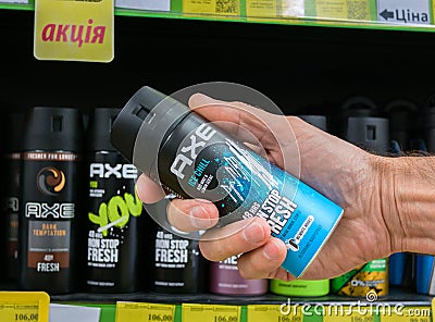 Axe Ice Chill 48H Non Stop Fresh men's spray deodorant in a man's hand against the background of shelves Editorial Stock Photo