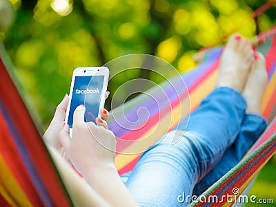 ZAPORIZHZHYA, UKRAINE - SEPTEMBER 20, 2014: Young Woman Using Facebook Application on her Smart Phone Editorial Stock Photo