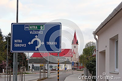 Zavar, Slovakia - April, 2011: blue pointer sign and Church of the Nativity of the Virgin Mary. Editorial Stock Photo