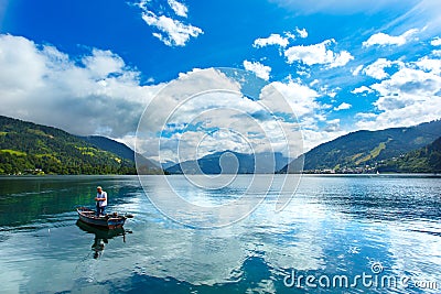 Zeller See lake. Zell Am See, Austria, Europe. Fisherman at foreground, Alps at background. Editorial Stock Photo