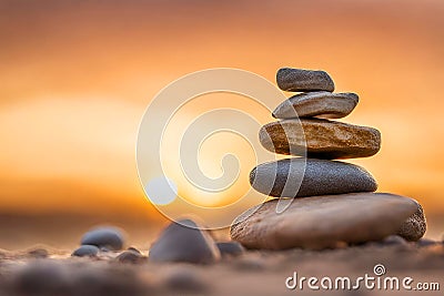 Zen stones stacked forming a pyramid on rocks, against the backdrop of the sunset, symbolizing harmony. Stock Photo