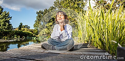 Zen young yoga child meditating alone to breathe near water Stock Photo