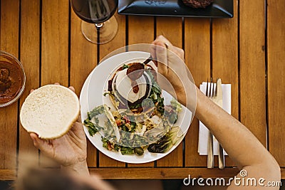 zenithal shot of a woman pouring hot sauce on a burger Stock Photo