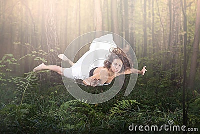 Zero gravity. Young beautiful woman flying in a dream. Forest green and glow Stock Photo