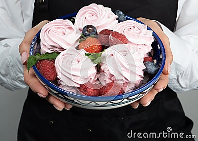 Zhenschina holds a Plate with homemade marshmallows, decorated with berries. No face. Bakery advertising concept, cooking secrets Stock Photo