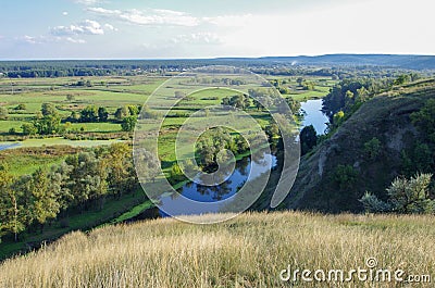 Zigzag river flows between summer valleys Stock Photo