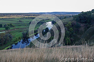 Zigzag river flows between summer valleys Stock Photo