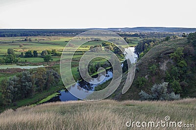 Zigzag river flows between summer valleys Stock Photo