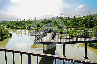 Zigzag steel footbridge over river in sunny summer afternoon Stock Photo