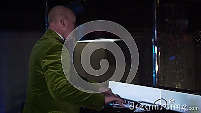 Zijaanzicht van de homoseksuele oude Blanke man die muziek op controlemechanisme mengen en aan bezoekers in nachtclub golven. Meer stock footage Zijaanzicht van de homoseksuele oude Blanke man die muziek op controlemechanisme mengen en aan bezoekers in nachtclub golven. Meer stock footage