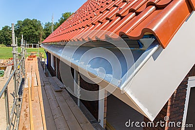 Zinc rain gutter with roof tiles and scaffolding Stock Photo