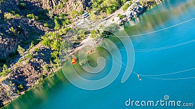 Zipline. Human in the equipment slides on a steel cable. Trolley Track Over the lake. Extreme and active rest Stock Photo