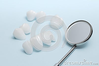 Dental mirror and Zircon dentures on a blue background - Ceramic veneers - lumineers Stock Photo