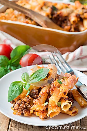 Ziti bolognese on white plate, pasta casserole with minced meat, tomato sauce and cheese, vertical Stock Photo