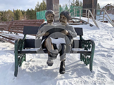 Zlatoust, Chelyabinsk region, Russia, January, 19, 2020. Sculpture `Couple reading on a bench` in the mountain Park named after P. Editorial Stock Photo