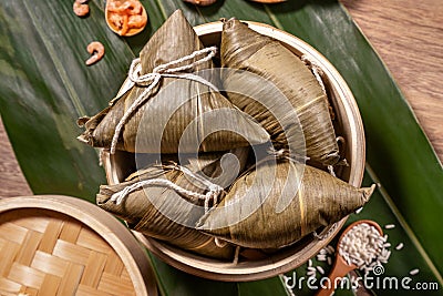 Zongzi, steamed rice dumplings on wooden table bamboo leaves, food in dragon boat festival duanwu concept, close up, copy space, Stock Photo