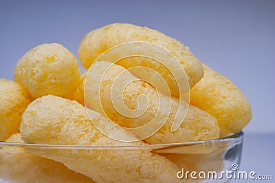 Zoomed Corn Puffs in a Glass Bowl. Crunchy Flavored Puffed Snacks. Party, Movie Snacks Stock Photo
