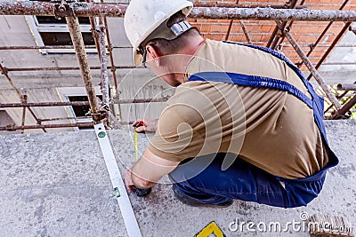 Civil engineer is marking point with pencil on concrete at building site Editorial Stock Photo