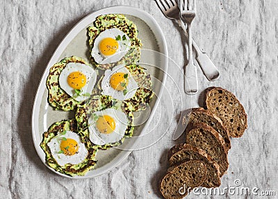 Zucchini fritters with fried quail eggs. Delicious breakfast or snack on a gray table, top view. Stock Photo