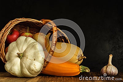 zucchini in a lying wicker basket. traditional autumn still life of vegetables on a black concrete background. artistic dark Stock Photo