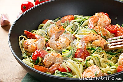 Zucchini noodles sauteed with cherry tomato and prawns in a pan Stock Photo