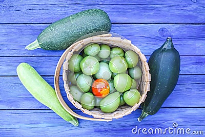 Zucchini and unripe tomatoes on wooden boards outdoors Stock Photo