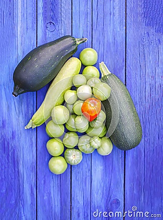 Zucchini and unripe tomatoes on wooden boards outdoors Stock Photo