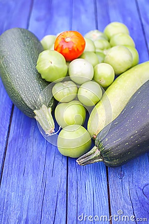 Zucchini and unripe tomatoes on wooden boards outdoors Stock Photo