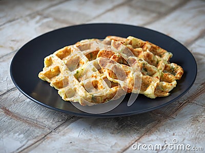 Zucchini waffles with the addition of greens and cheese on a close plate standing on a wooden decorative table Stock Photo