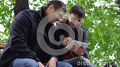Zwei junge Leute benutzen eine Tablette im Park stock video Zwei junge Leute benutzen eine Tablette im Park stock video