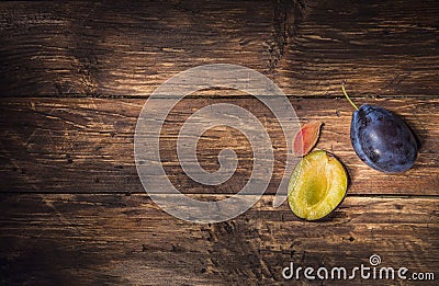 Ðžne single plum and a half of plum with stone over dark board. Fruit background. Text space. Top view. Stock Photo